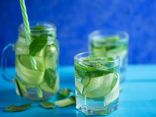 Cucumber infused water with mint on wooden blue background