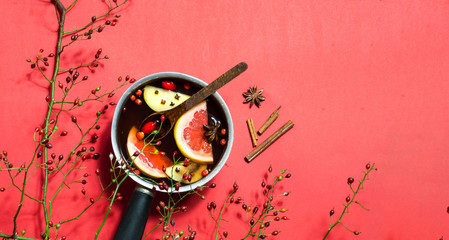 Hot mulled wine with ingredients in authentic ladle on living coral background.