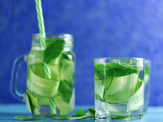Cucumber infused water with mint on wooden blue background