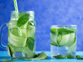 Cucumber infused water with mint on wooden blue background
