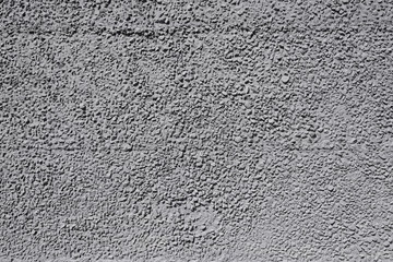 Textured concrete wall with gray, sharp stones.