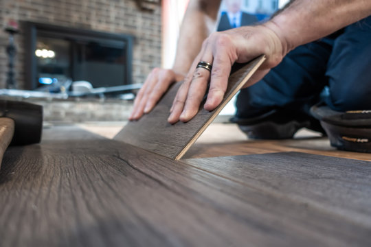 Man Installing Engineered Laminate Wood Floring Indoor