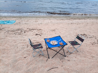 Fototapeta premium Lunch by the sea, tourist folding furniture, chairs and a table.
