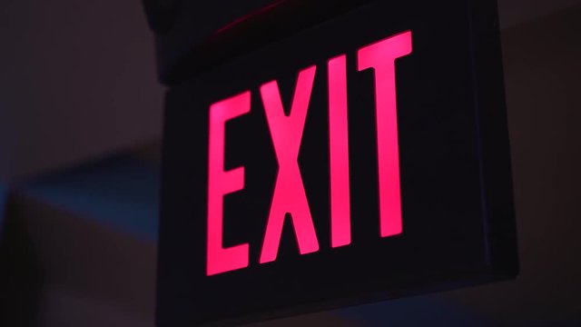 Red exit sign lit up in dark room 4k