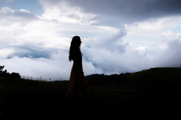 Silhouette of young woman with far clouds 