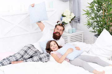Obraz na płótnie Canvas Happy fatherhood. Man bearded hipster with childish hairstyle colorful ponytails and daughter in pajamas. Guy and girl relaxing in bedroom. Pajamas style. Having fun pajamas party. Slumber party