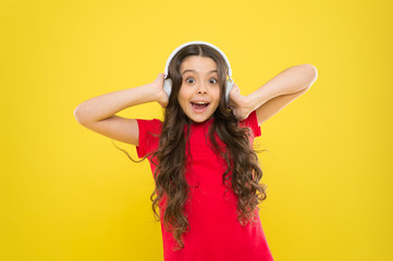 Naklejka premium Give in to the groove. Little DJ on yellow background. Cute girl listening to music in DJ headphones. Small child using wireless headset for DJ disco. Adorable kid enjoying DJ tune playing in radio