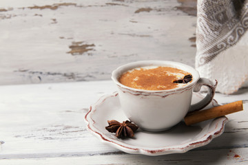 Beautiful cup of traditional indian masala chai tea on with star anise and cinnamon on a shabby wooden texture background