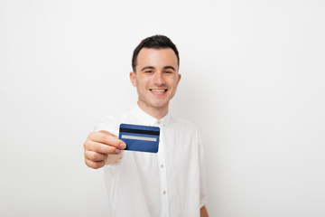 cheerful young man in white suit holds a card credit