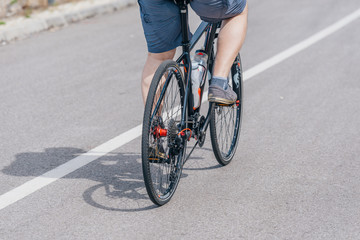 A caucasian male biker rides his bike uphill, wearing professional biking mountain biking gear