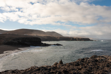Ocean shore with high hills and cliffs at Ajuy beach, Fuerteventura, Canary Islands, Spain. 