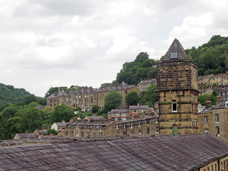 a view of the steep hillside streets in hebden bridge between summer trees with the tower of the historic nutclough mill building at the front © Philip J Openshaw 