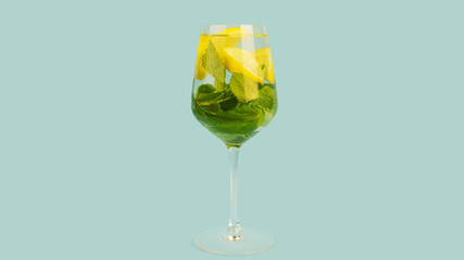Glass of refreshing cocktail on blue background. Copy space, 16:9. Gin tonic alcoholic drink with lemon, lime and mint. Summer bar concept.