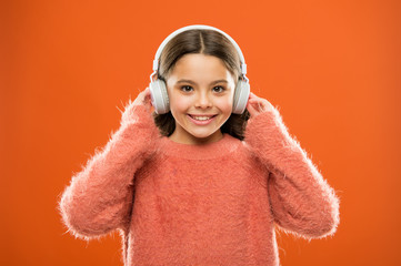 Perfect sound stereo headphones. Girl cute little child wear headphones listen music. Kid listen music orange background. Recommended music based on initial interest. Music produces pleasure