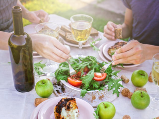 People eat in the garden at the table. Dinner concept with wine in the fresh air. Grilled sea fish and salads with vegetables and herbs. Mediterranean Kitchen. Horizontal shot