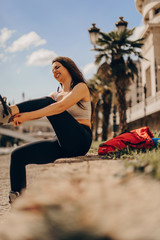 Female trying hard to put skates on in the center of the city