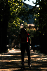 Young woman wearing roller skates outdoor, low key, dark image
