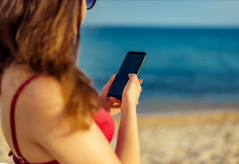 Female hands texting message on mobile phone on seaside