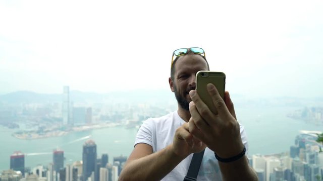 Young man taking selfie photo with cellphone at Hong Kong viewpoint
