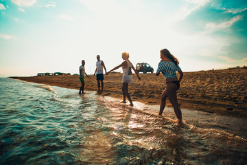 Fototapeta premium Group of happy friends jogging in to water at summer