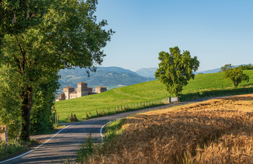 Castle surrounded by green fields and wheat fields in Italy