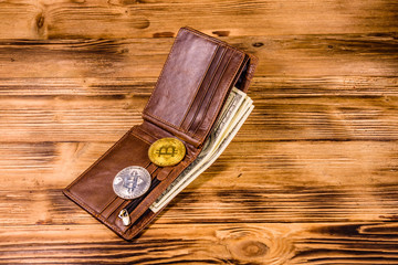 Brown leather wallet, bitcoins and one hundred dollar banknotes on the wooden background