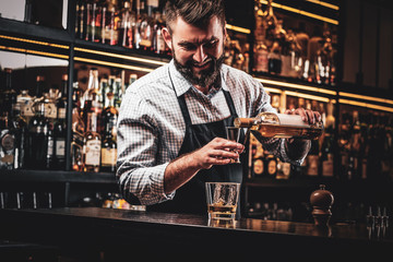Diligent happy barman is preparing alcoholic beverege for customer.