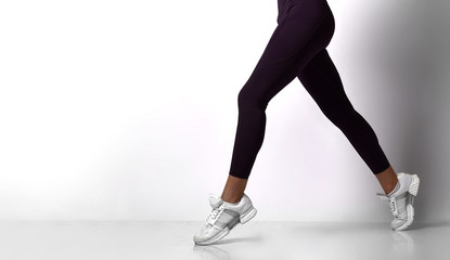 Fototapeta na wymiar Sporty woman legs walking in sport wear on a white