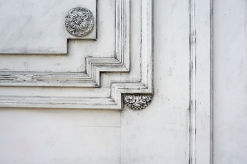 Fragment of a wooden carved door painted with white paint. Architectural background with empty space