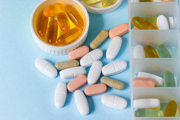 Tablets and capsules of drugs in containers and on the table.