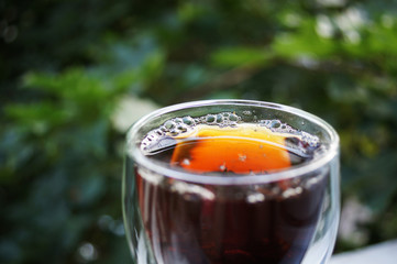 Black tea in clear glass cup on the nature on green blurred background.