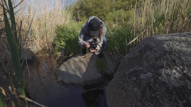 A young woman traveler photographer walks in the mountains at canyon. Shoots river on camera