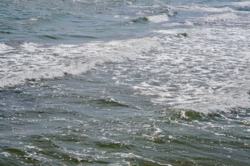 Sonnige Meeresfläche mit kleinen Wellen und Schaum