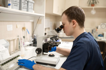 Laboratory assistant looking through microscope. Make research in laboratory. Science and medicine concept