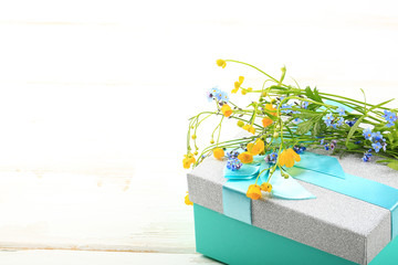 wild flowers on gift box on white wooden background