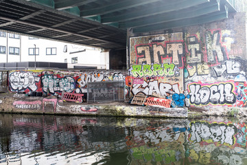 Hackney, East London, England, UK - April 2019: Murals and graffiti below a railway bridge along Regent's canal near Broadway Market, East London