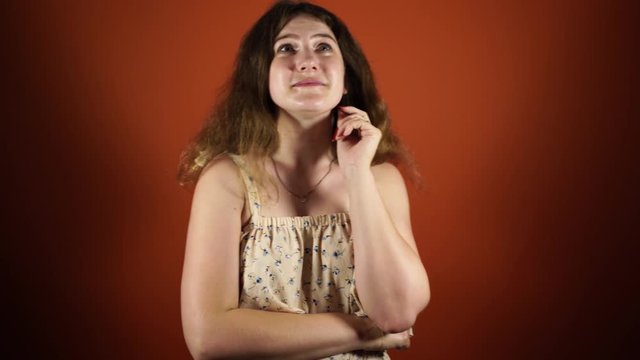 Pensive woman thinking and having an idea isolated over orange background
