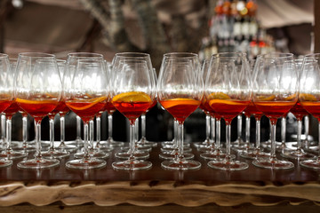 A lot of cocktails at the bar at the wedding party. Glasses with apperol and with a slice of lemon close-up