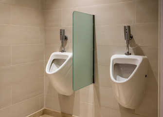Pair of modern porcelain urinals with automatic flush in male bathroom