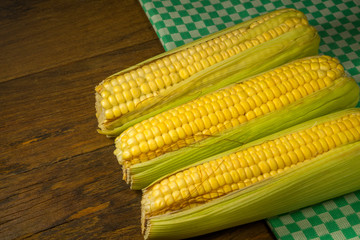 Fresh corn on cobs on rustic wooden table