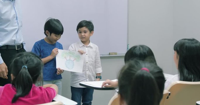 Little boy present drawing picture at front of classroom for saving world project. Volunteer, Nature and Education concept.