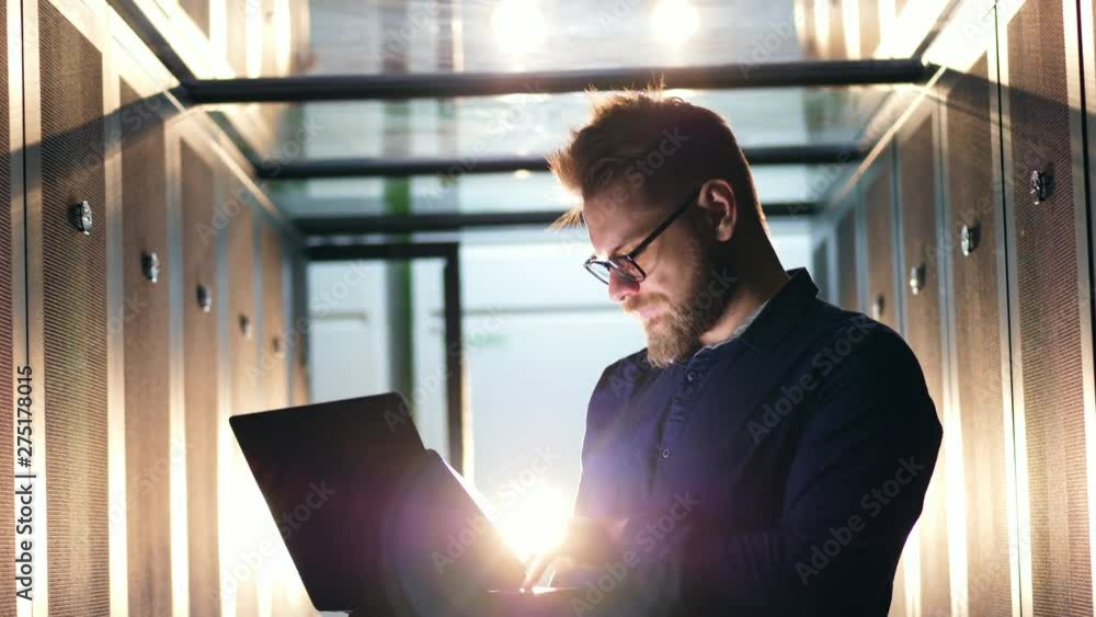 Aufkleber server room with a man operating a laptop in a flashlight. datacenter server room concept.
