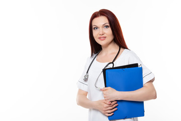 Happy young female family doctor holds blue folder with documents, has friendly expression, isolated white background. Medicine concept.