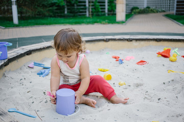 Baby girl in sandbox playing with toys