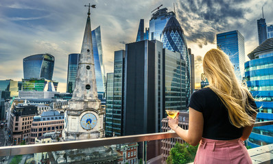 Aerial view of skyscrapers of the world famous bank district of central London at sunset and woman...