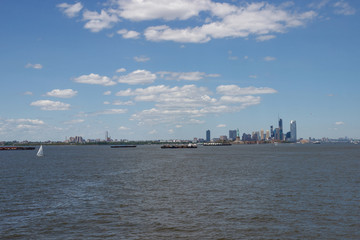 Naklejka premium On the horizon are seen the skyscrapers of New York. Skyscrapers of New York in the distance. Bay, blue sky, sunny summer day in New York.