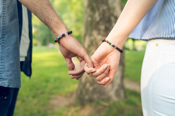 Young couple in love relationship holding hands in park midsection close up