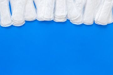 Menstruation calendar concept with sanitary pads on blue background top view space for text