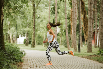  A beautiful fitness girl runs in the park. Nature and healthy life