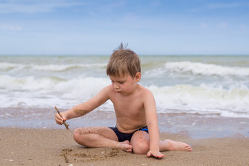 Fototapeta na wymiar A little boy plays near the water by the sea.